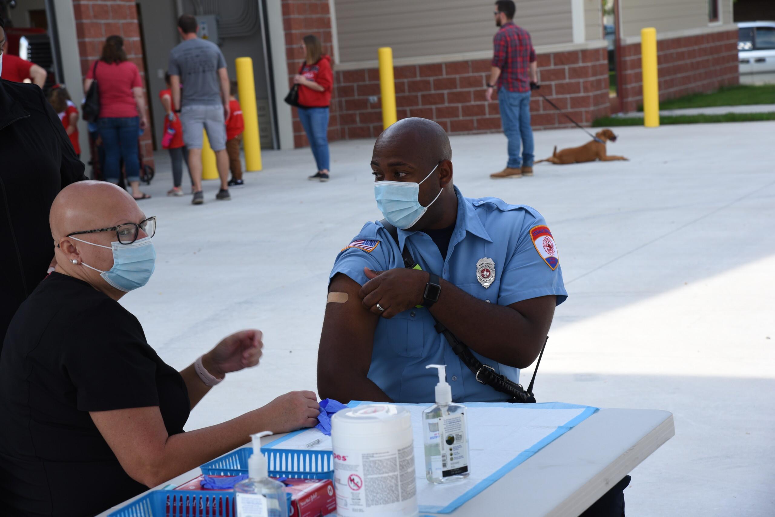 Image of uniformed firefighter and medical worker at vaccination clinic